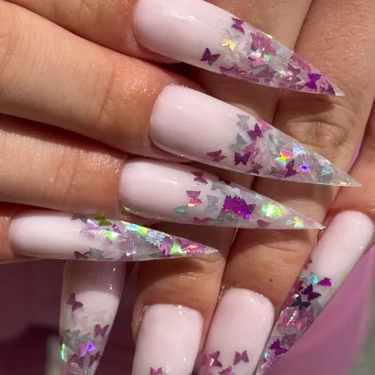 Long pale pink stilettos with clear tips full of holographic butterfly glitter