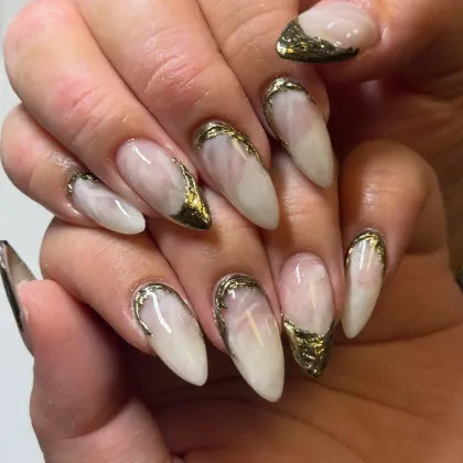 Long milky almond nails edged in gold chrome