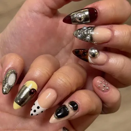 Almond nails, each one different: mirror chrome, tortoiseshell, polka dots, pastel yellow and studs
